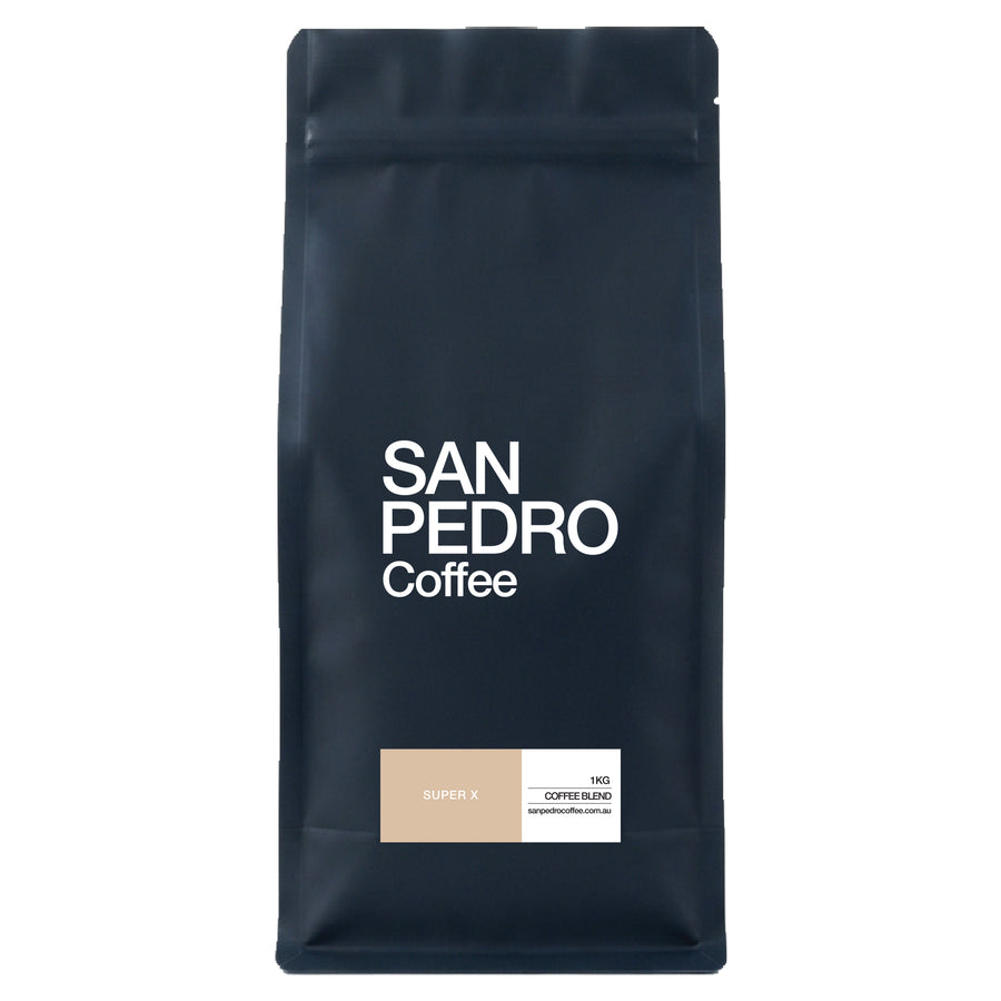 A dark navy blue stand-up pouch of San Pedro Coffee Super X coffee blend, featuring white text and a small beige and white label near the bottom, set against a plain white background.