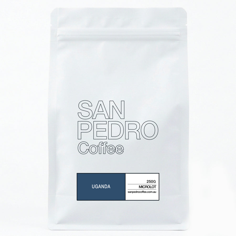 A white stand-up coffee bag with a resealable zipper at the top. The front is printed with the brand name 'SAN PEDRO Coffee' in outlined gray text, and a dark blue label at the bottom left reading 'UGANDA' alongside smaller black text on the right.